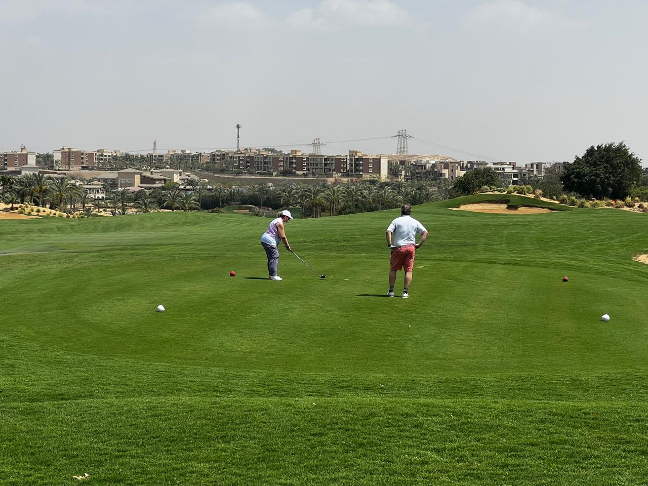 Golfers on a lush Cairo fairway under clear winter skies