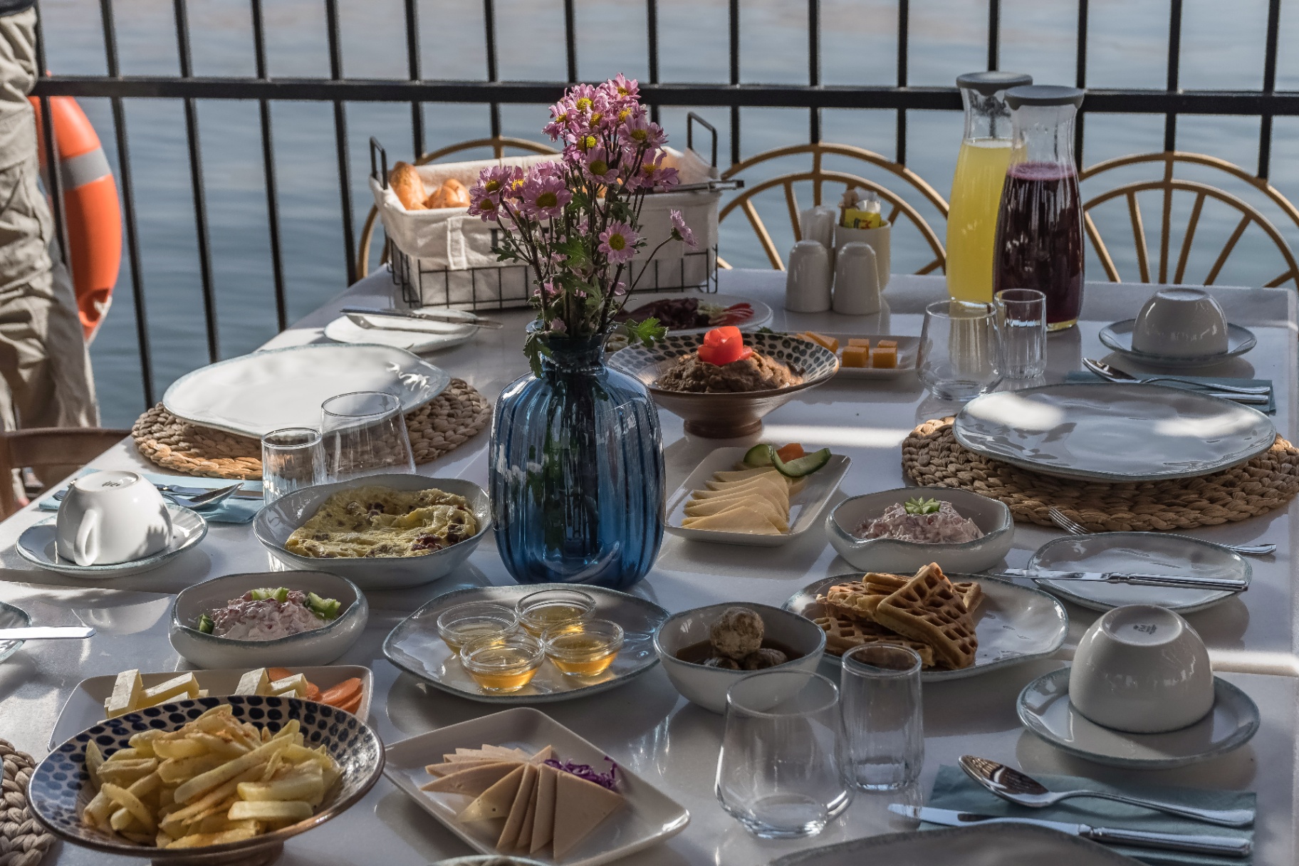 Elegant Egyptian breakfast spread on Cleo Dahabiya with waffles, mezze, honey and fresh juices, the Nile just behind