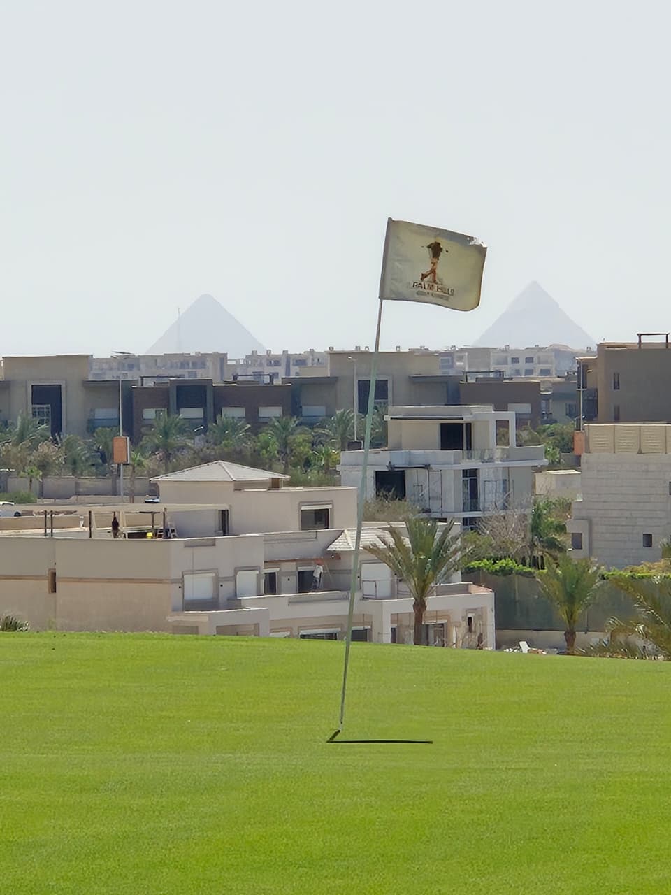 Palm Hills golf green with the Pyramids of Giza on the horizon